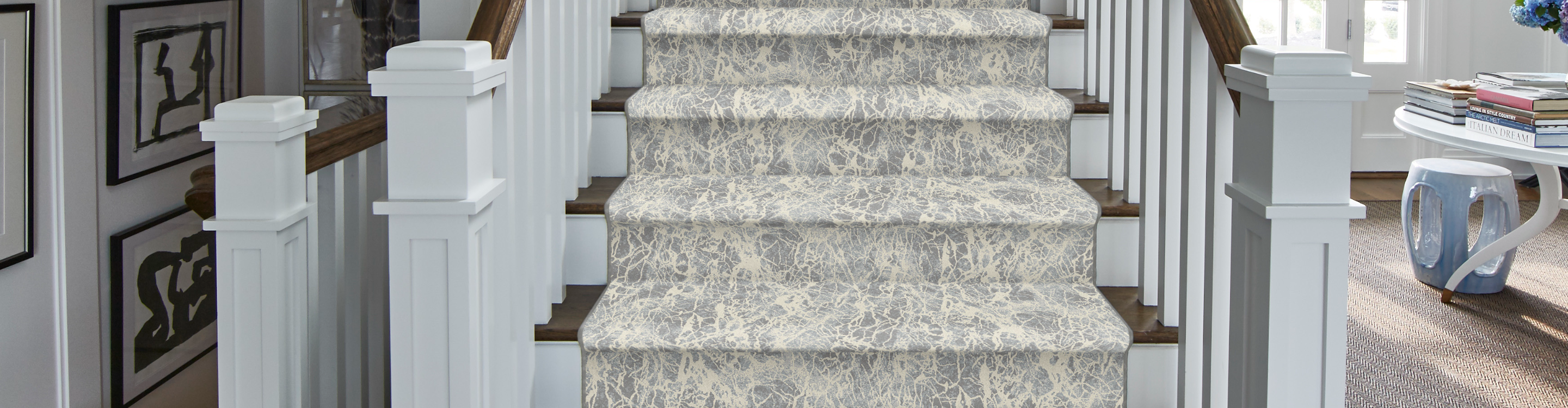 Patterned carpet stair runner on hardwood staircase. 